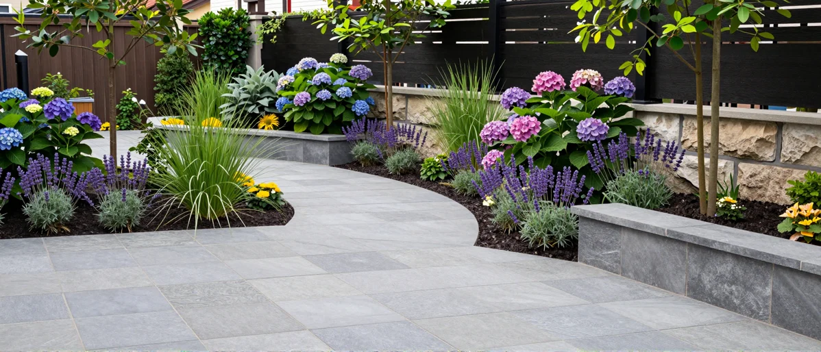 Frisch bepflanztes Gartenbeet neben einer Terrasse mit Lavendel, Hortensien, Straeuchern und Ziergraesern