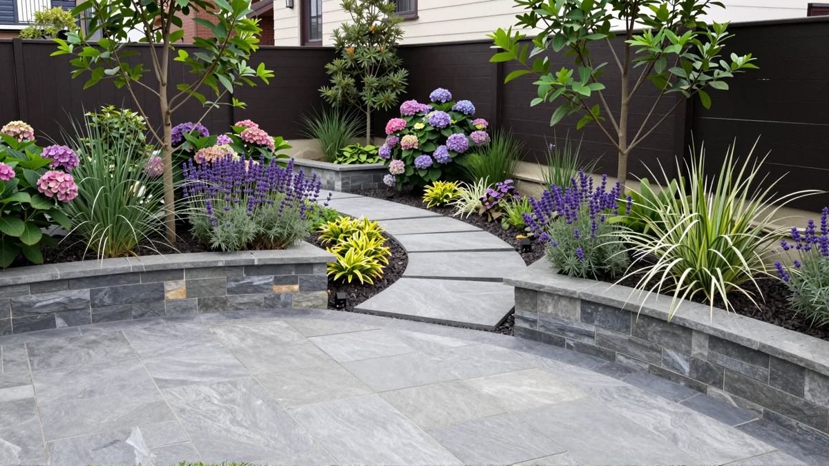 Frisch bepflanztes Gartenbeet neben einer Terrasse mit Lavendel, Hortensien, Straeuchern und Ziergraesern