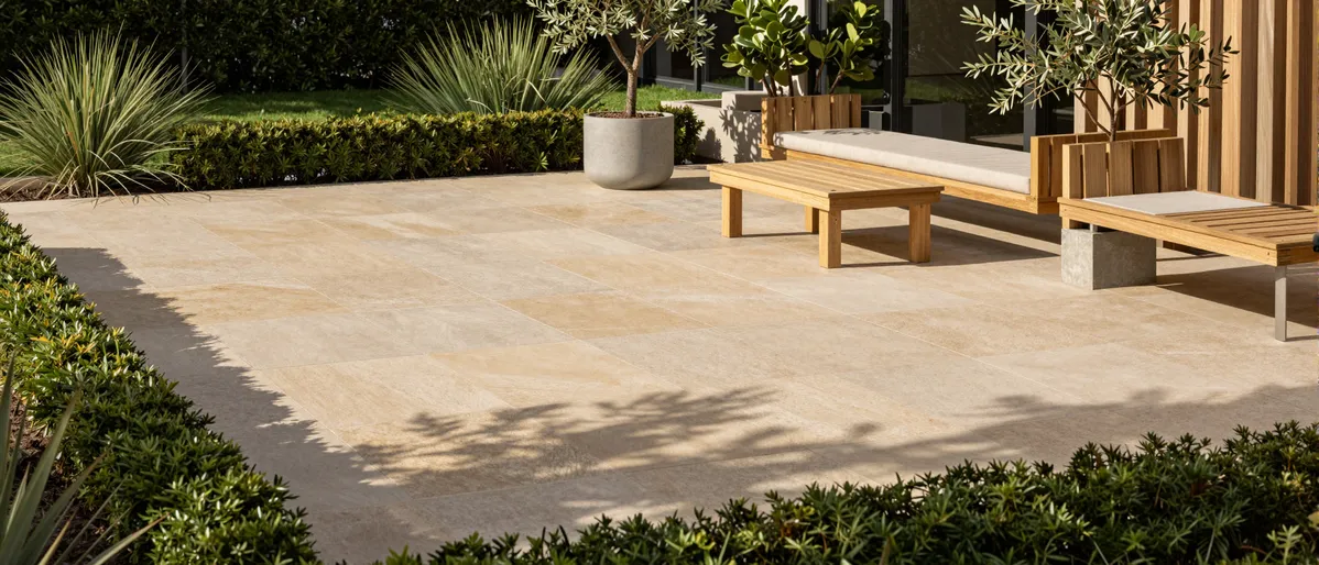 Moderne Gartenterrasse mit geometrischen Steinplatten, minimalistischen Möbeln und Olivenbäumen in Betonpflanzkübeln