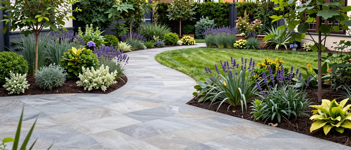 Frisch bepflanztes Gartenbeet neben einer Terrasse mit Lavendel, Hortensien, Straeuchern und Ziergraesern