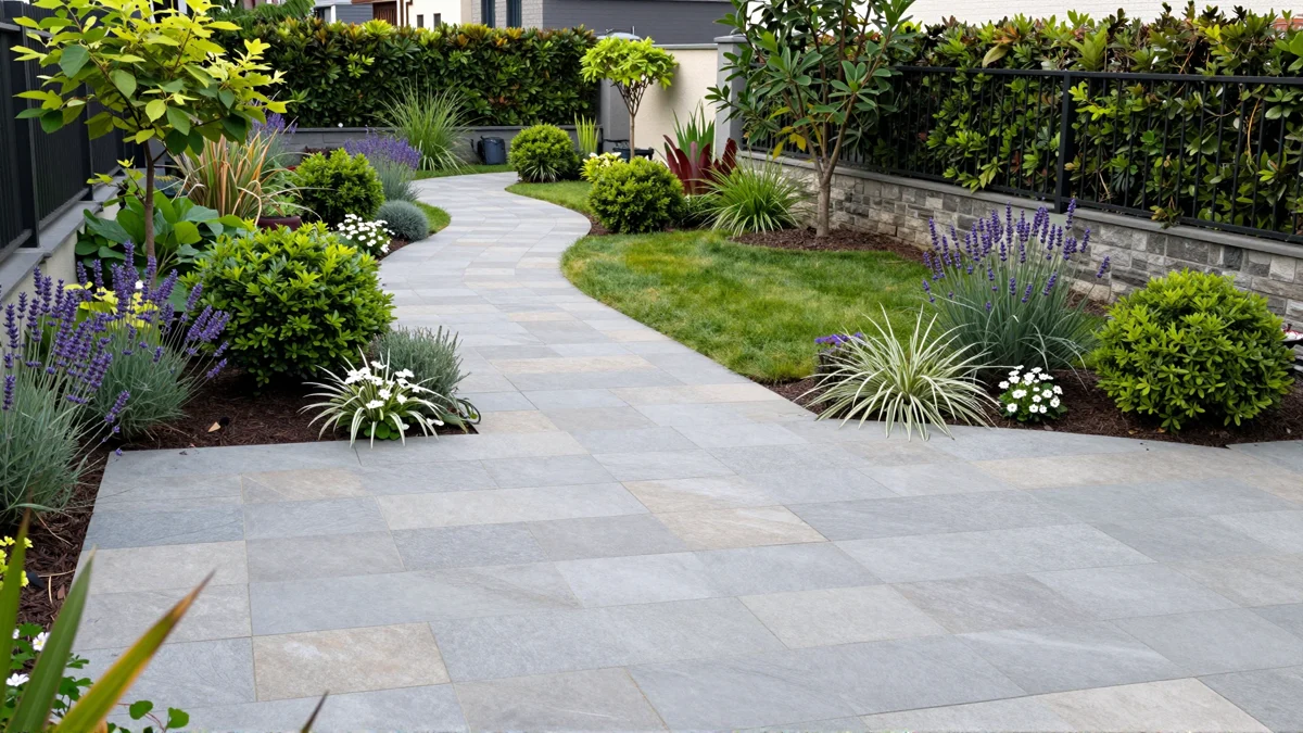 Frisch bepflanztes Gartenbeet neben einer Terrasse mit Lavendel, Hortensien, Straeuchern und Ziergraesern
