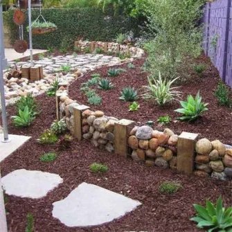 Steingarten mit Pflanzflächen und Natursteinmauer