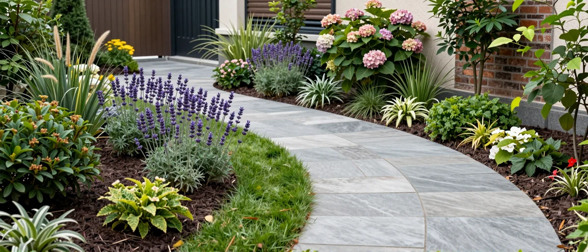 Frisch bepflanztes Gartenbeet neben einer Terrasse mit Lavendel, Hortensien, Straeuchern und Ziergraesern