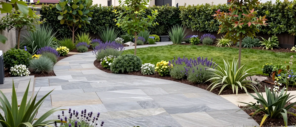 Frisch bepflanztes Gartenbeet neben einer Terrasse mit Lavendel, Hortensien, Straeuchern und Ziergraesern