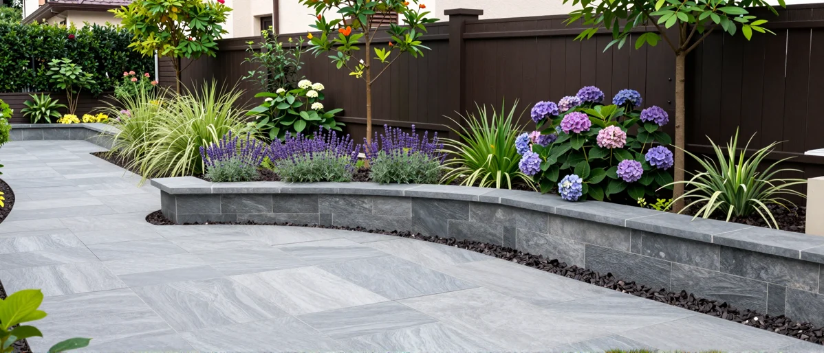 Frisch bepflanztes Gartenbeet neben einer Terrasse mit Lavendel, Hortensien, Straeuchern und Ziergraesern