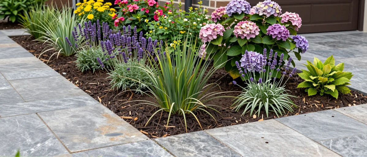 Frisch bepflanztes Gartenbeet neben einer Terrasse mit Lavendel, Hortensien, Straeuchern und Ziergraesern